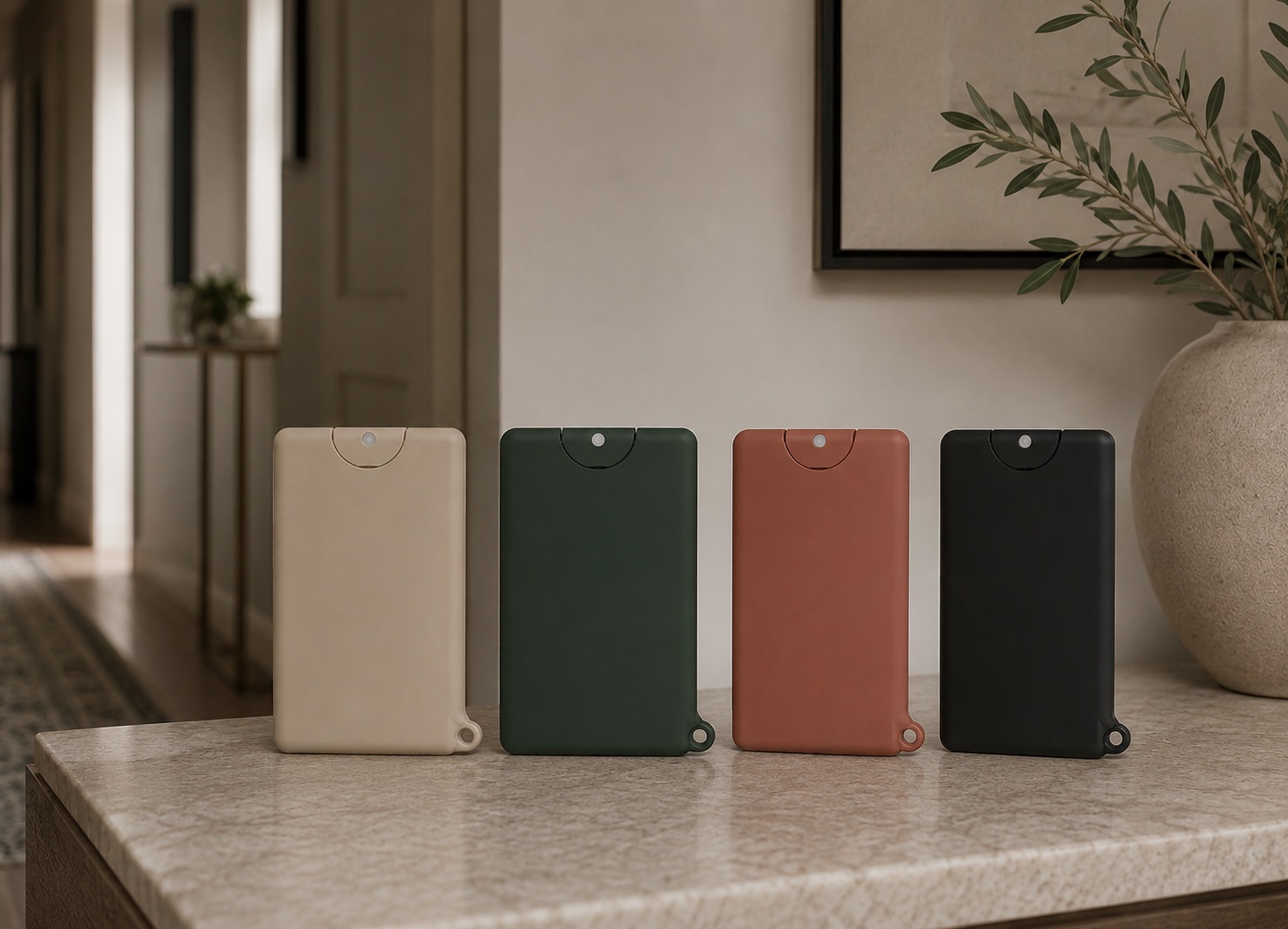Four Pocket Mist devices in Sandstone, Forest Green, Terracotta and Charcoal standing on a marble countertop